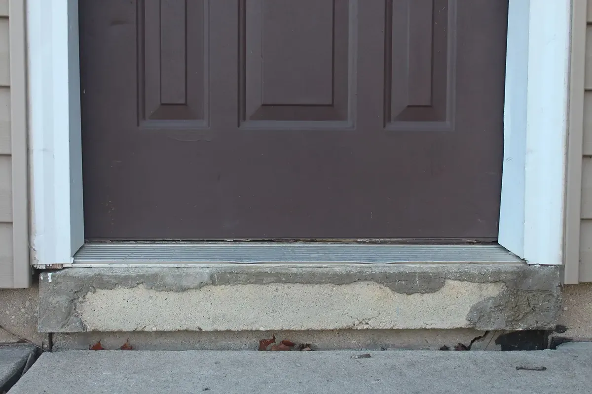 Brown door with white trim against sunkin concrete.